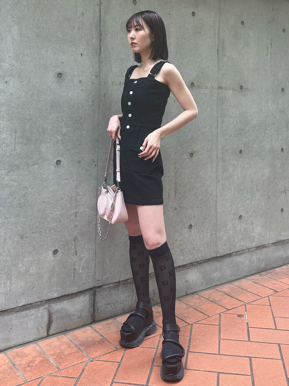 ブラック系のワンピース、ブラック系のサンダル、ピンク系のショルダーバッグを着用したレディースの春コーディネートの2枚目の写真