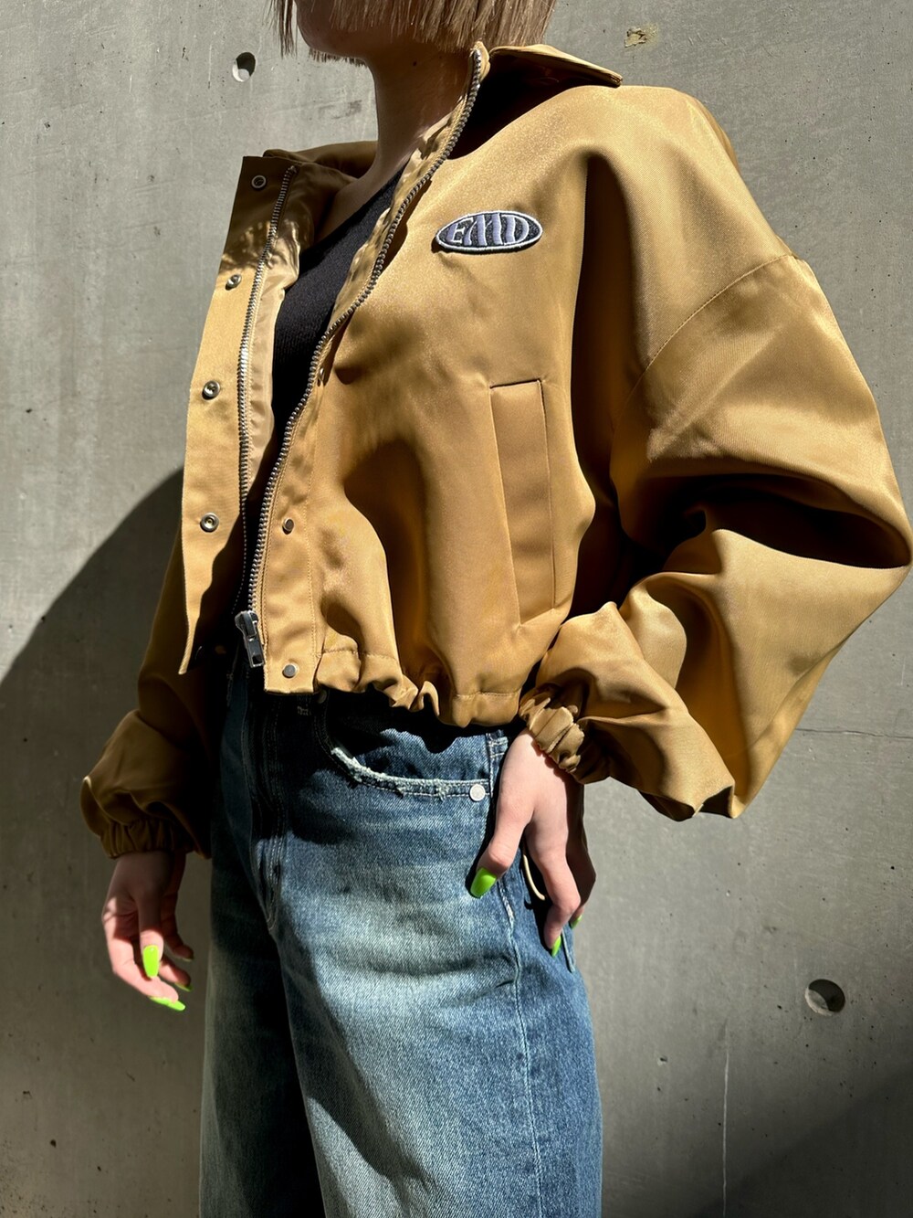 ベージュ系のブルゾン、ブルー系のデニムパンツを着用したレディースの冬コーディネートの2枚目の写真