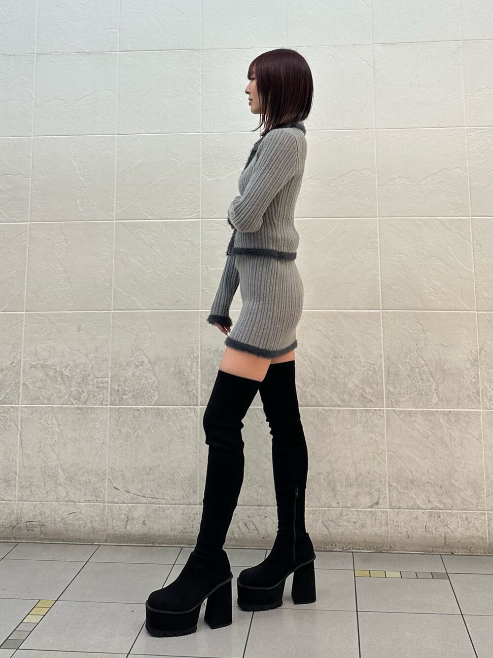 グレー系のニット/セーター、グレー系のスカート、ブラック系のブーツを着用したレディースの秋コーディネートの2枚目の写真
