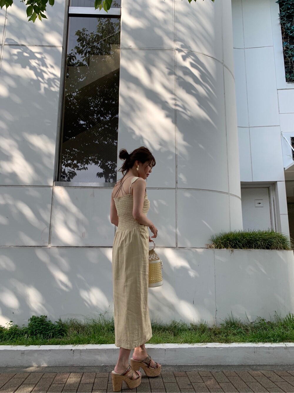 ホワイト系のハンドバッグ、イエロー系のワンピース、ゴールド系のピアス（両耳用）を着用したレディースの夏コーディネートの2枚目の写真