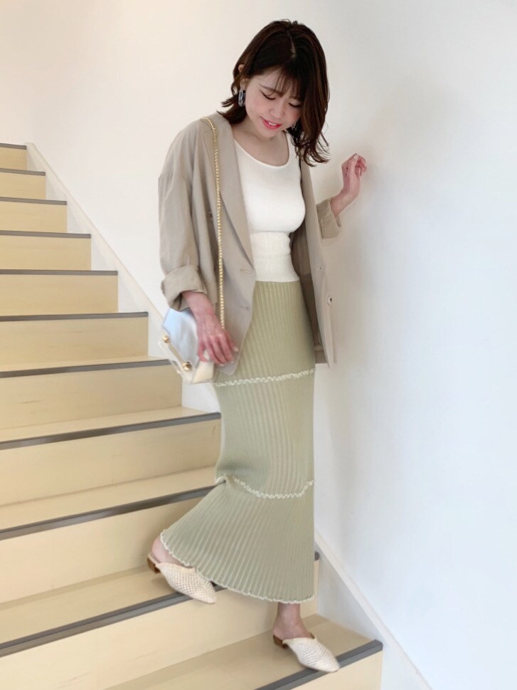 ベージュ系のパンプス、イエロー系のスカート、ホワイト系のニット/セーターを着用したレディースの春コーディネートの2枚目の写真