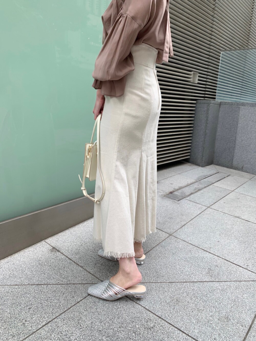 ホワイト系のスカート、シルバー系のサンダル、ホワイト系のハンドバッグを着用したレディースの冬コーディネートの8枚目の写真