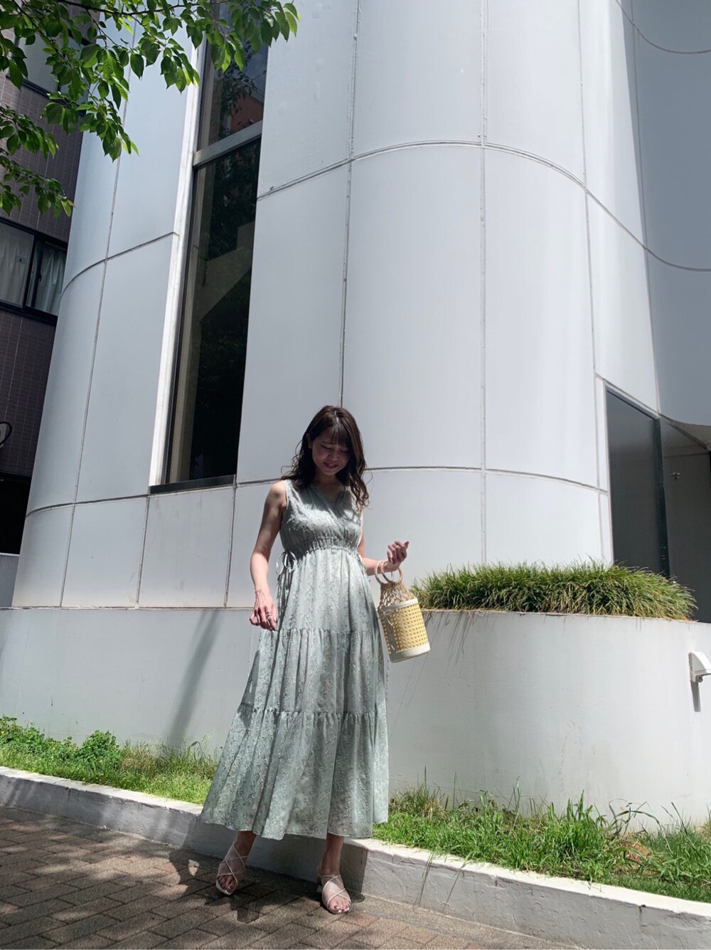 ホワイト系のハンドバッグ、グリーン系のワンピース、ベージュ系のサンダルを着用したレディースの夏コーディネートの2枚目の写真