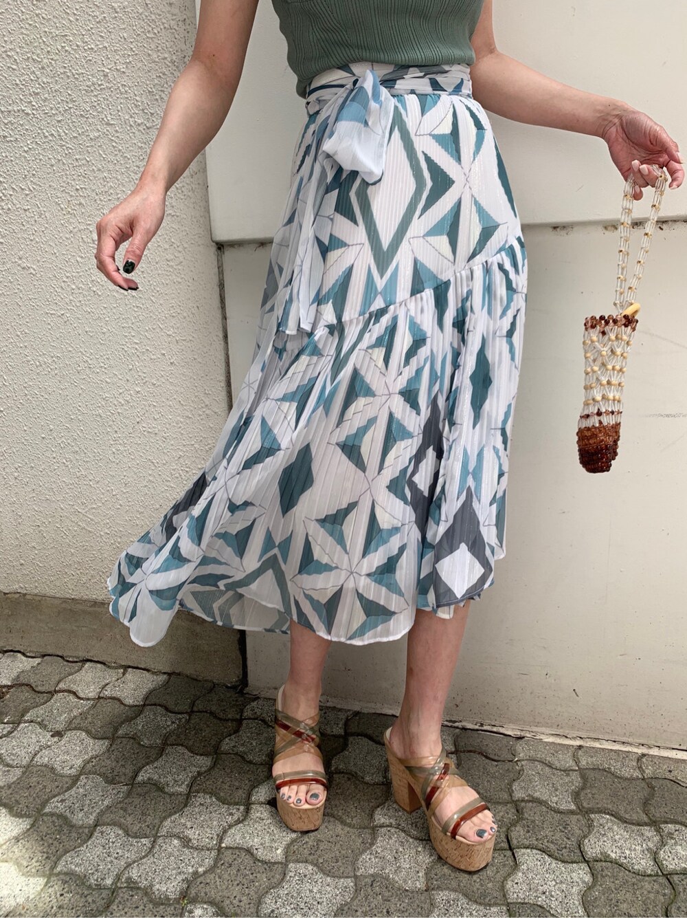 グリーン系のサンダル、ブルー系のスカート、グリーン系のニット/セーターを着用したレディースの春コーディネートの2枚目の写真