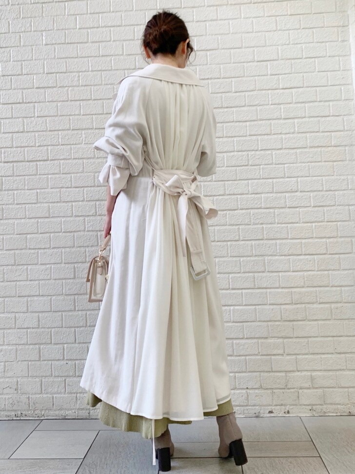 ホワイト系のトレンチコート、グリーン系のワンピースを着用したレディースの冬コーディネートの2枚目の写真