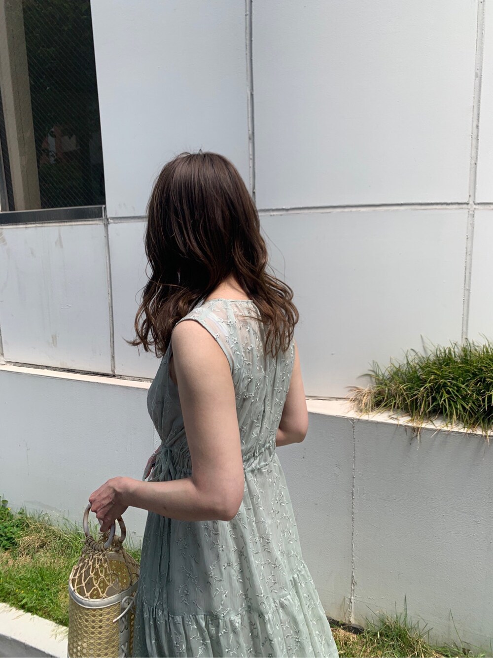 ホワイト系のハンドバッグ、グリーン系のワンピース、ベージュ系のサンダルを着用したレディースの夏コーディネートの4枚目の写真