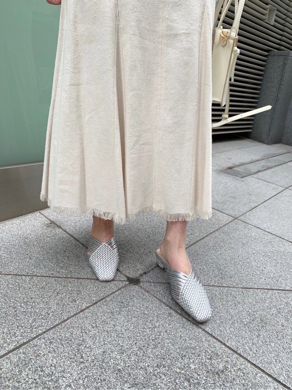 ホワイト系のスカート、シルバー系のサンダル、ホワイト系のハンドバッグを着用したレディースの冬コーディネートの7枚目の写真