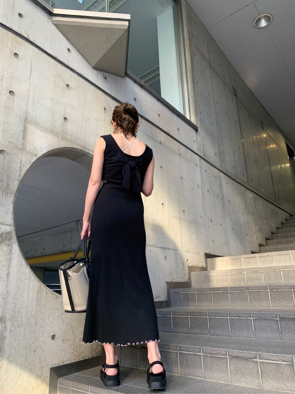 ブラック系のトートバッグ、ブラック系のサンダルを着用したレディースの春コーディネートの2枚目の写真