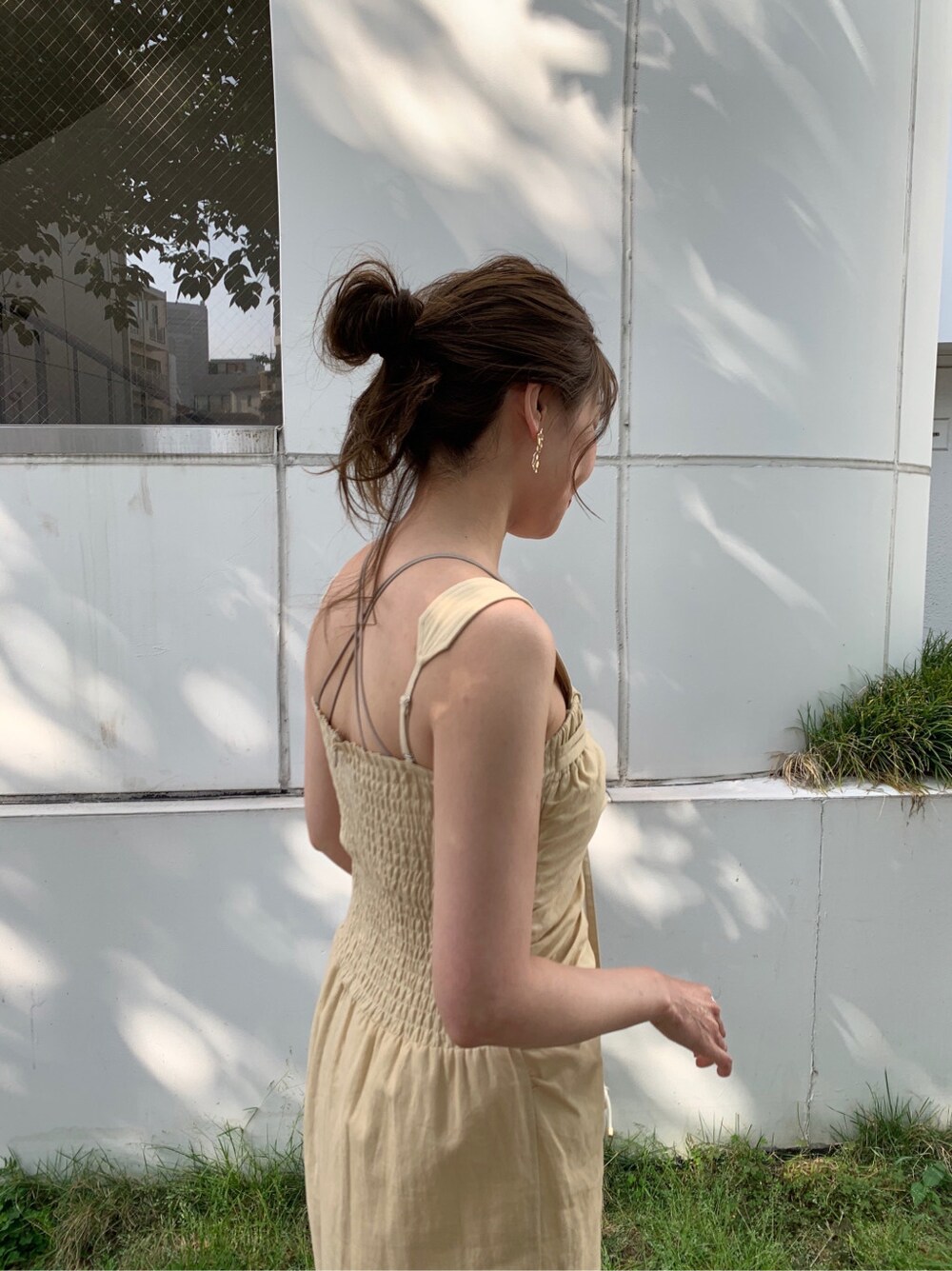 ホワイト系のハンドバッグ、イエロー系のワンピース、ゴールド系のピアス（両耳用）を着用したレディースの夏コーディネートの4枚目の写真