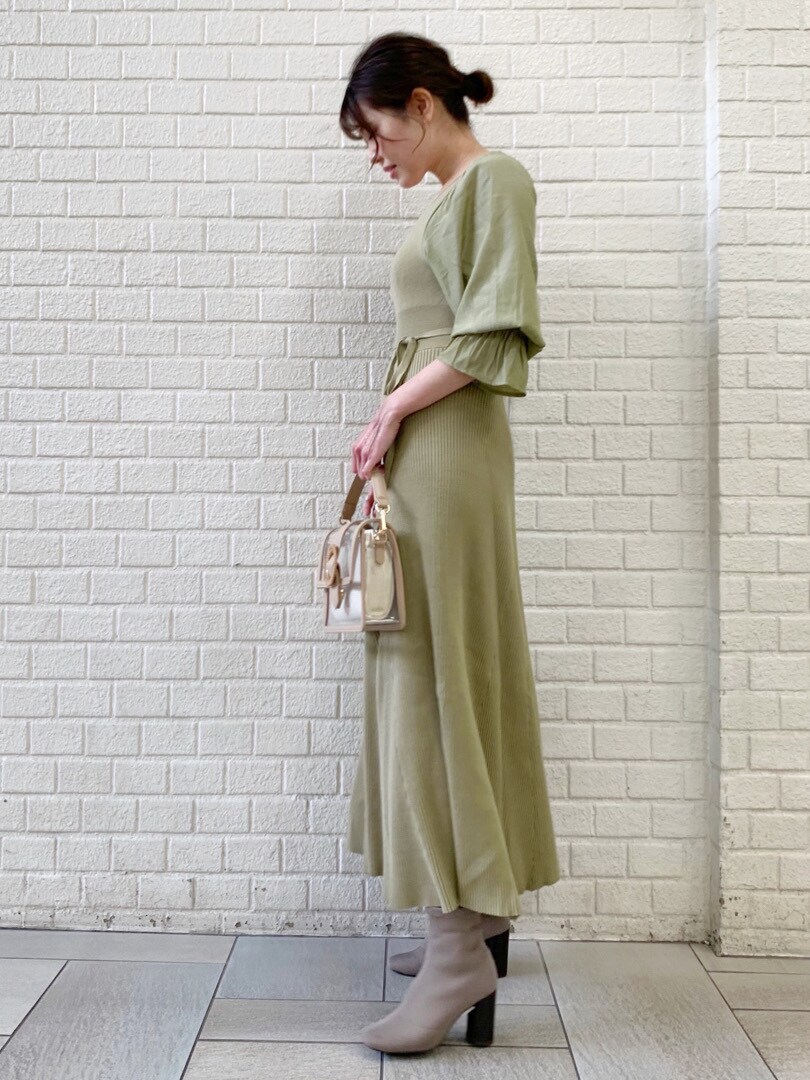 ホワイト系のトレンチコート、グリーン系のワンピースを着用したレディースの冬コーディネートの2枚目の写真