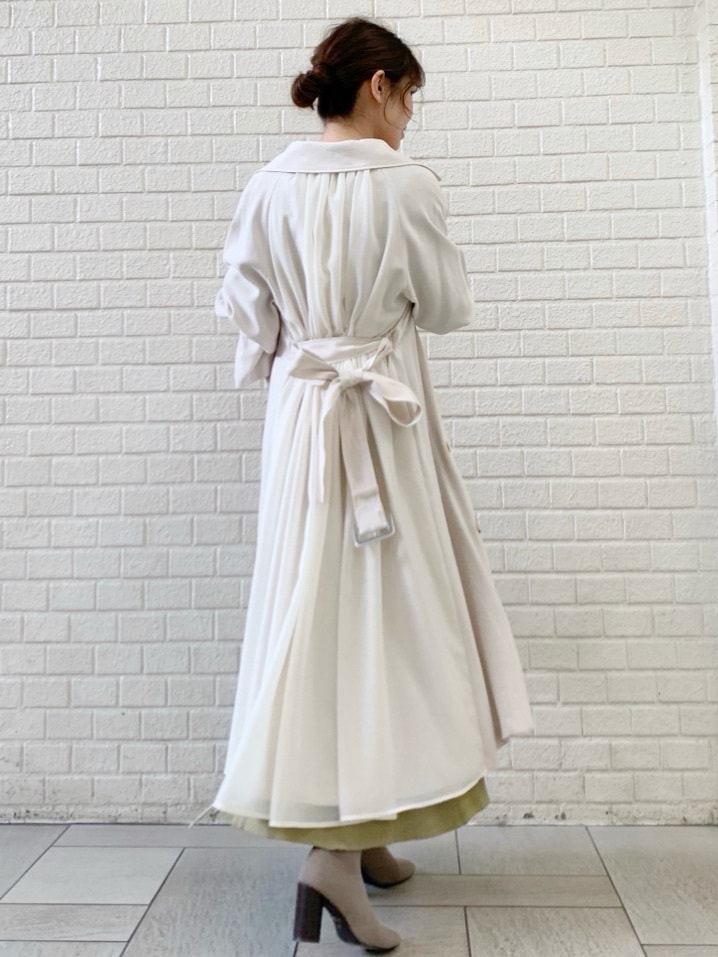 ホワイト系のトレンチコート、グリーン系のワンピースを着用したレディースの冬コーディネートの5枚目の写真