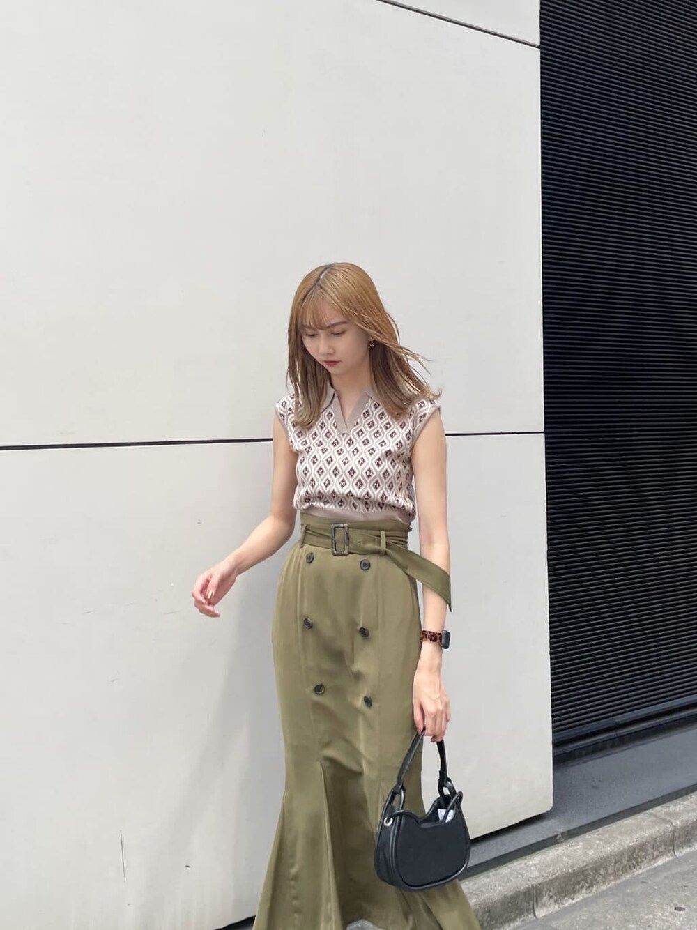 ベージュ系のスカート、ブラック系のハンドバッグ、ベージュ系のニット/セーターを着用したレディースの夏コーディネートの3枚目の写真