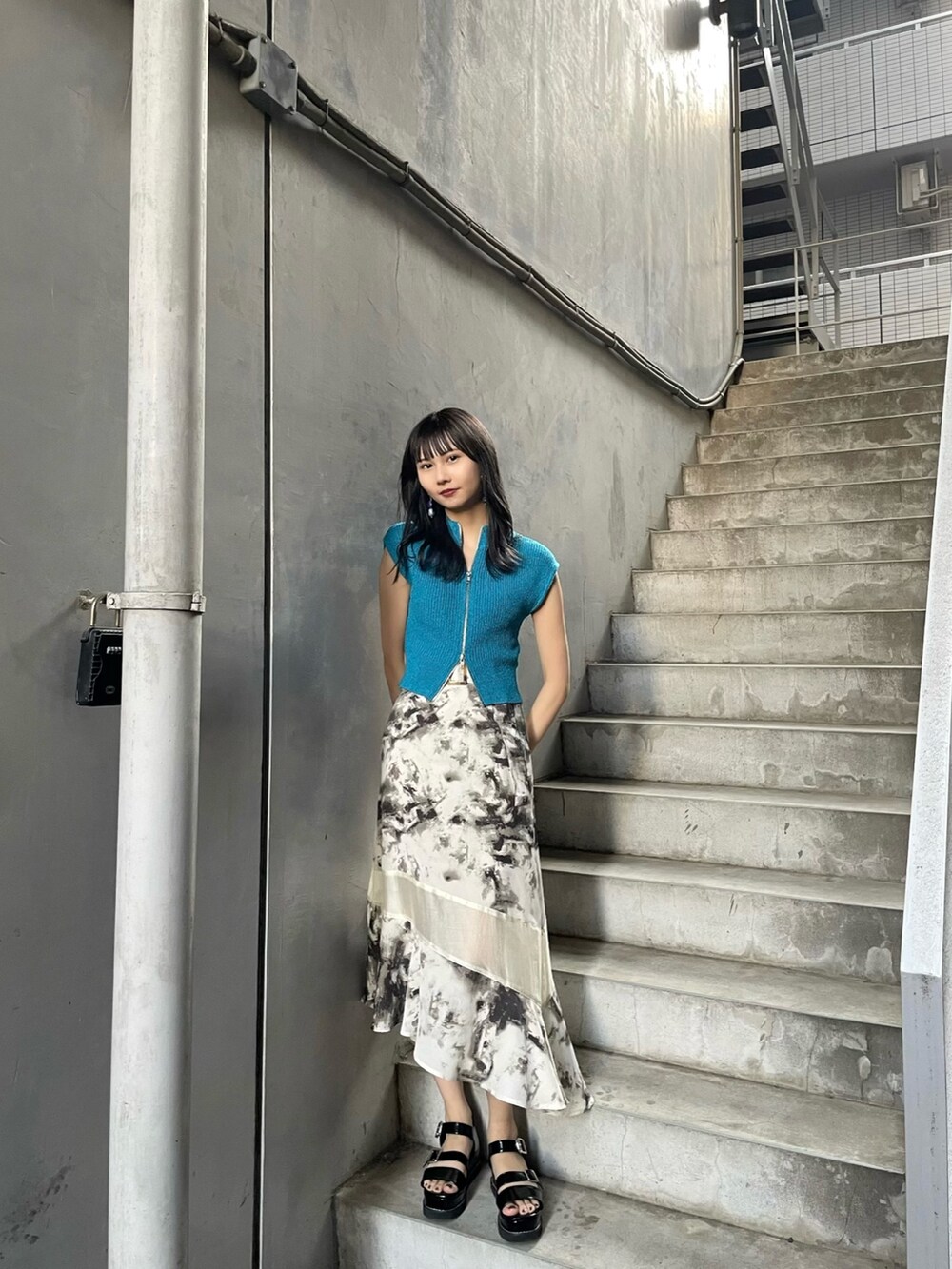 ブルー系のニット/セーター、その他のスカート、ブラック系のサンダルを着用したレディースの春コーディネートの2枚目の写真