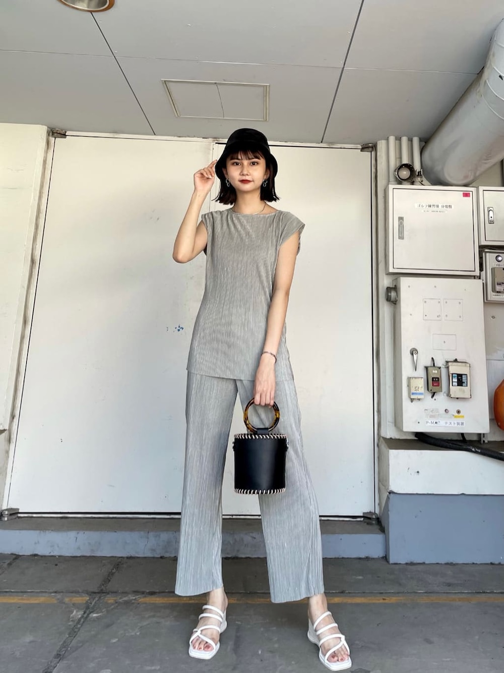 グレー系のスウェットパンツ、ブラック系のハンドバッグ、ホワイト系のサンダルを着用したレディースの夏コーディネートの2枚目の写真