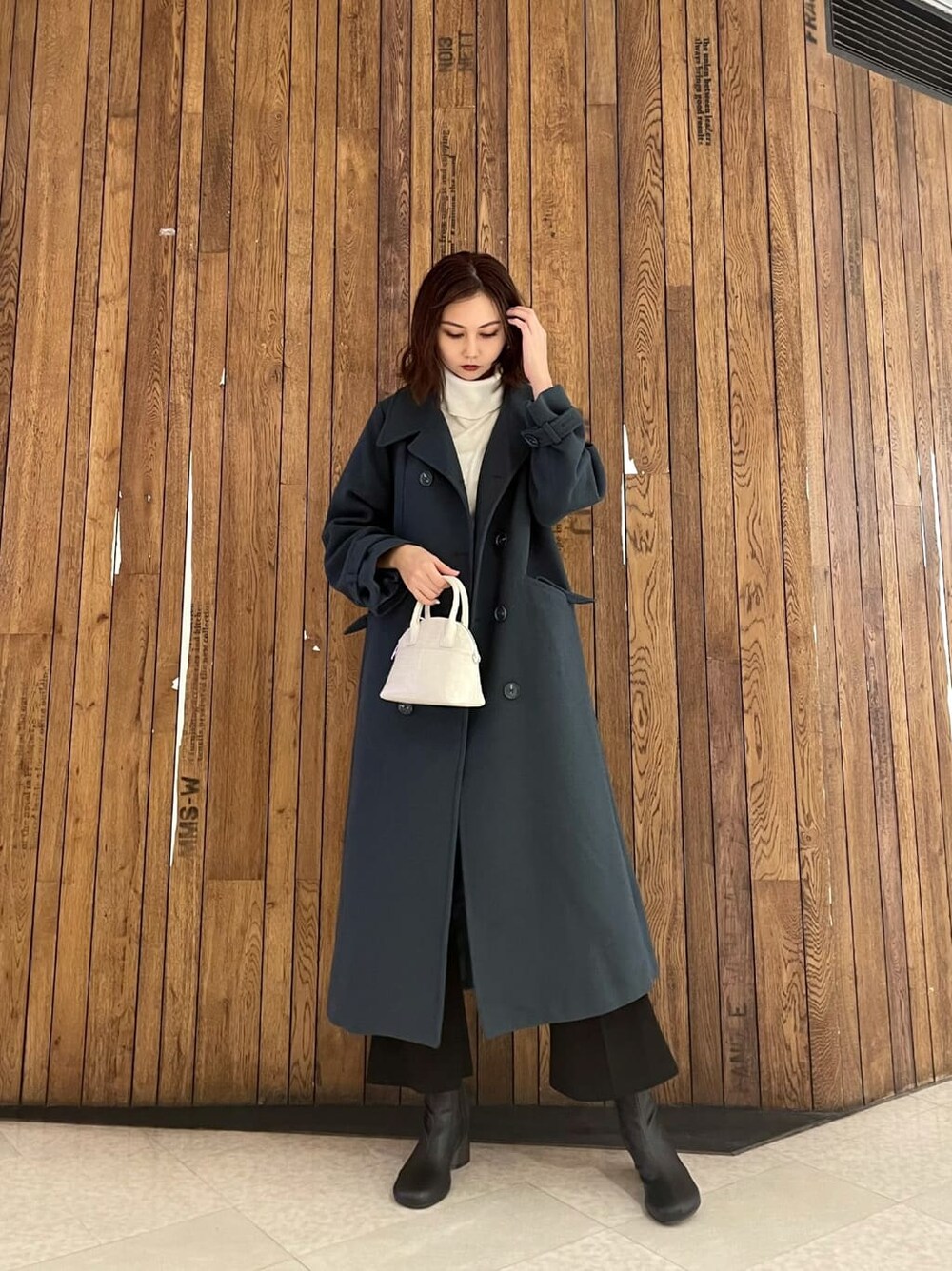 ブラック系のブーツ、ブラック系のその他パンツ、ホワイト系のハンドバッグを着用したレディースの秋コーディネートの2枚目の写真