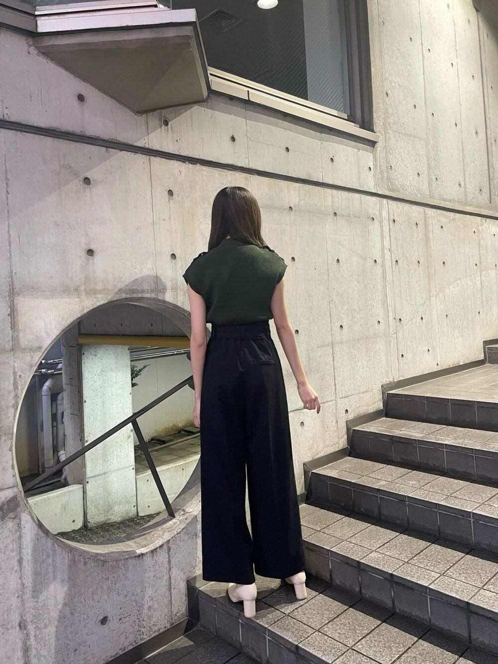 グリーン系のニット/セーター、ブラック系のスラックス、ホワイト系のブーツを着用したレディースの夏コーディネートの3枚目の写真