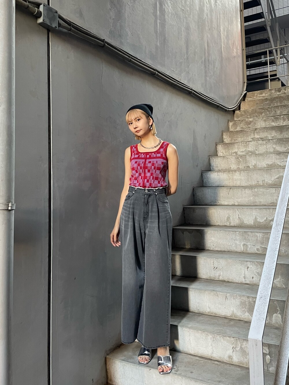 レッド系のタンクトップ、ブラック系のデニムパンツ、シルバー系のサンダルを着用したレディースの冬コーディネートの2枚目の写真