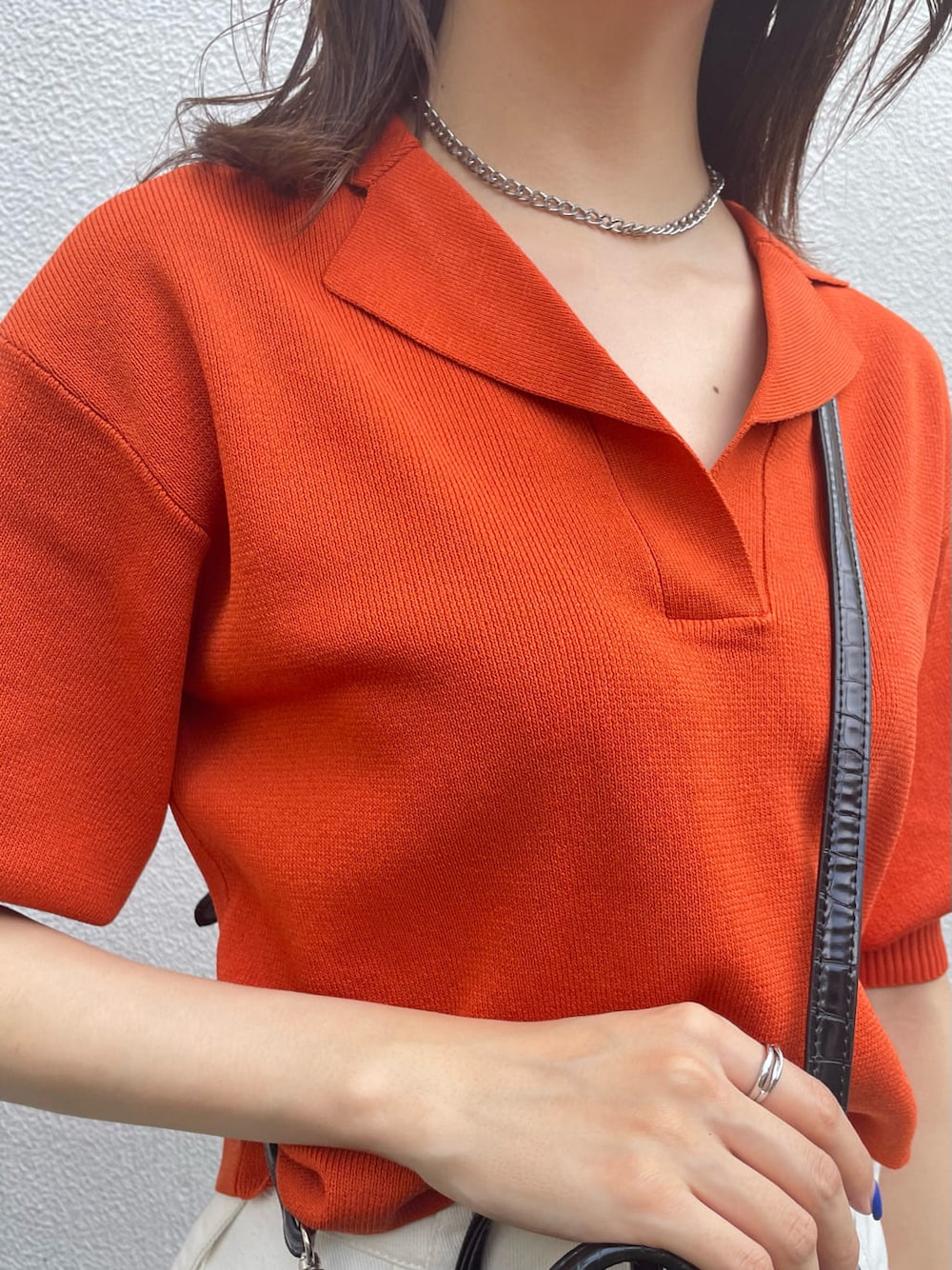 オレンジ系のポロシャツ、ホワイト系のデニムパンツ、ブラック系のサンダルを着用したレディースの夏コーディネートの5枚目の写真