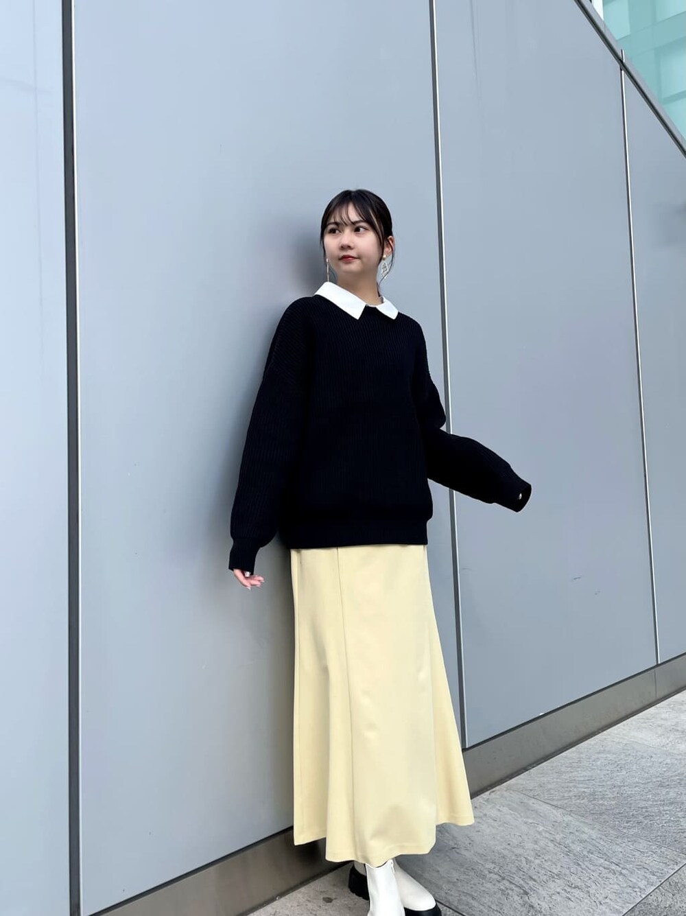 イエロー系のスカート、ホワイト系のブーツ、ブラック系のニット/セーターを着用したレディースの冬コーディネートの3枚目の写真