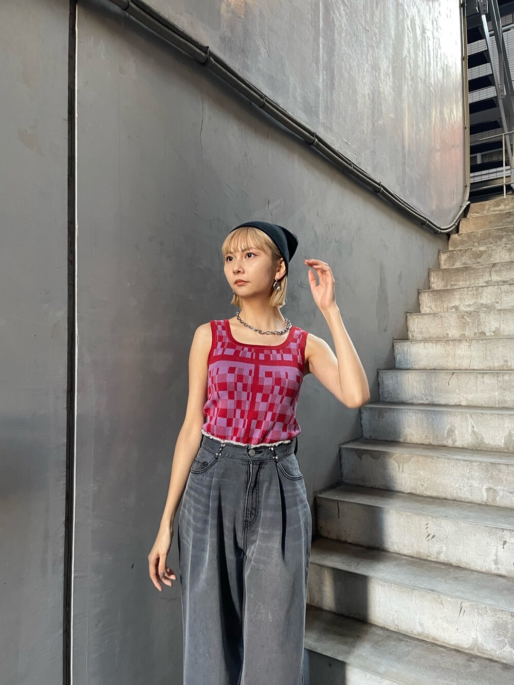 レッド系のタンクトップ、ブラック系のデニムパンツ、シルバー系のサンダルを着用したレディースの冬コーディネートの4枚目の写真