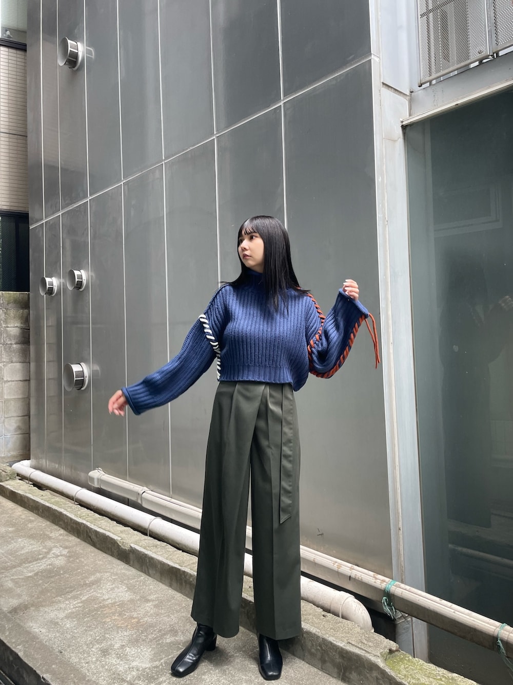 ブルー系のニット/セーター、グリーン系のスラックス、ブラック系のブーツを着用したレディースの夏コーディネートの2枚目の写真