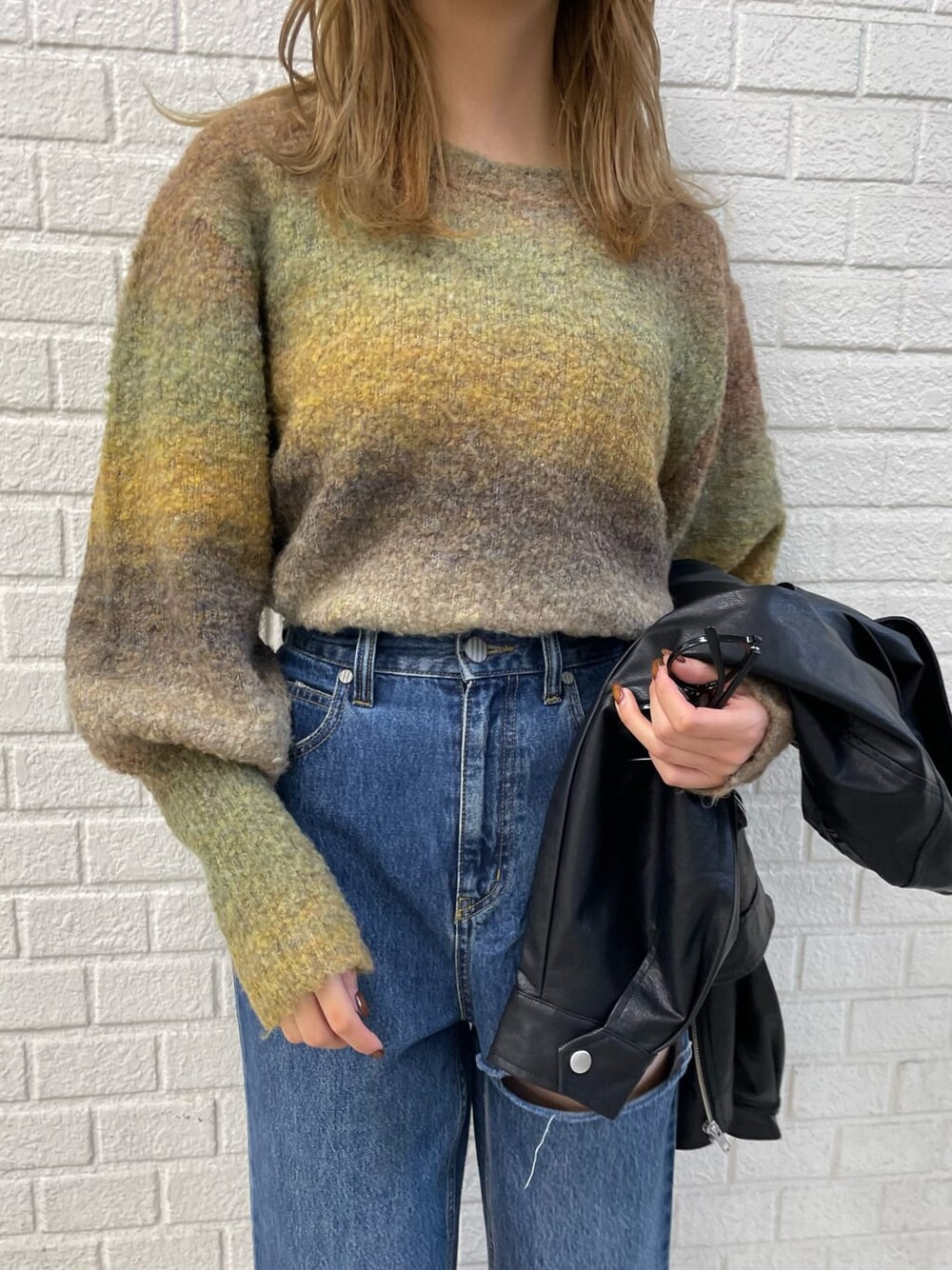 ブラック系のライダースジャケット、ホワイト系のブーツ、ブルー系のデニムパンツを着用したレディースの秋コーディネートの6枚目の写真