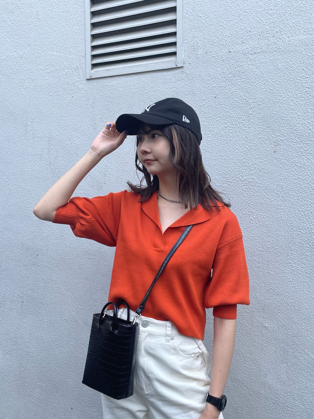 オレンジ系のポロシャツ、ホワイト系のデニムパンツ、ブラック系のサンダルを着用したレディースの夏コーディネートの4枚目の写真