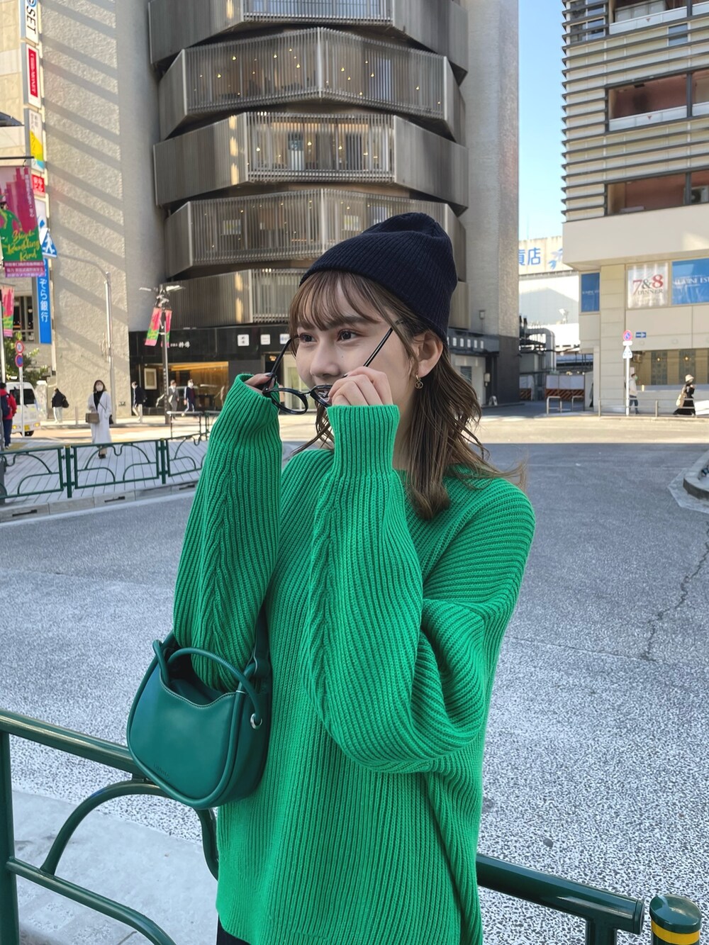 グリーン系のニット/セーター、グリーン系のハンドバッグ、ブラック系のスカートを着用したレディースの冬コーディネートの3枚目の写真
