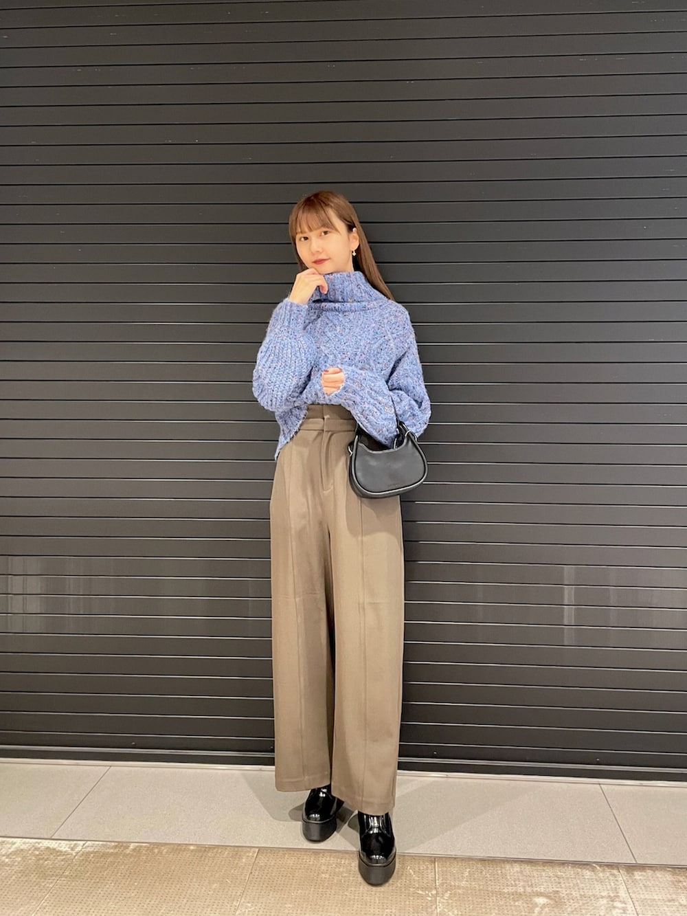 ブルー系のニット/セーター、ブラック系のハンドバッグ、ブラック系のブーツを着用したレディースの冬コーディネートの2枚目の写真