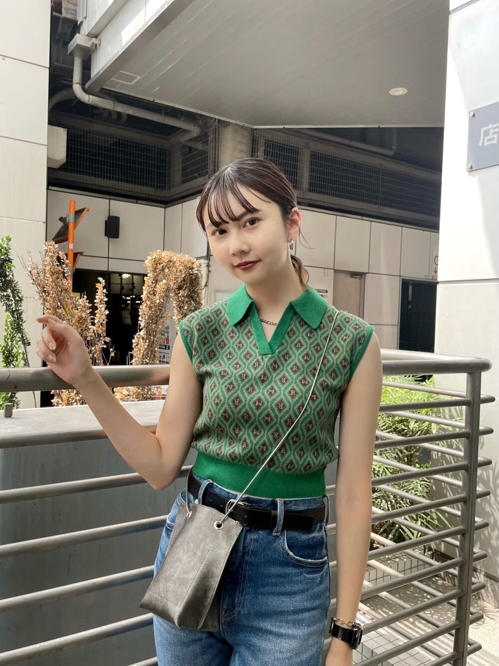 ブルー系のデニムパンツ、ブラック系のショルダーバッグ、グリーン系のニット/セーターを着用したレディースの夏コーディネートの4枚目の写真