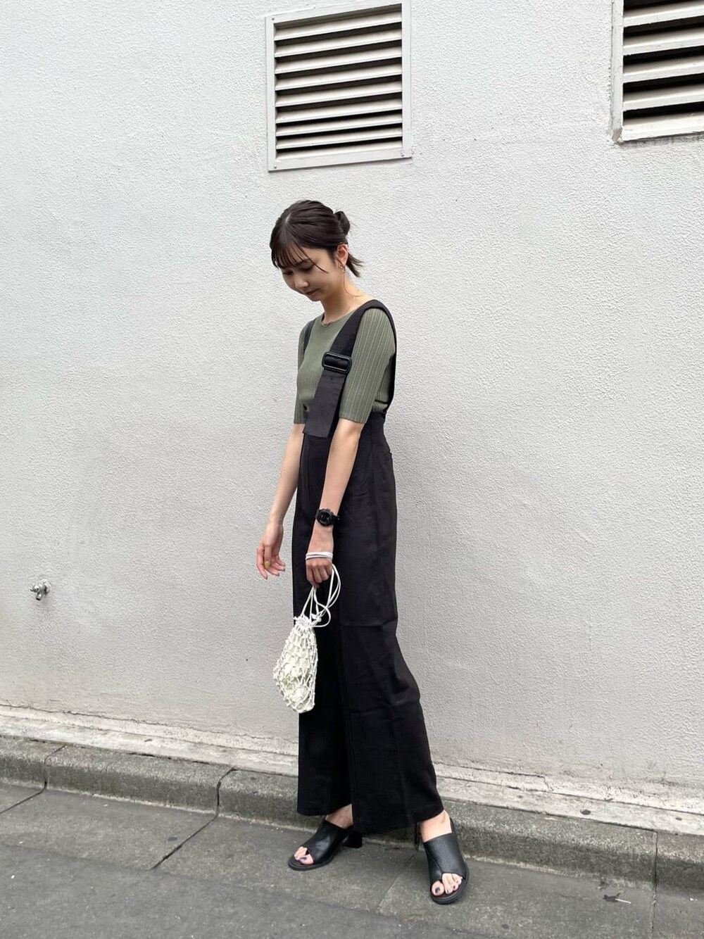 ブラック系のつなぎ/オールインワン、ホワイト系のハンドバッグ、グリーン系のニット/セーターを着用したレディースの春コーディネートの3枚目の写真