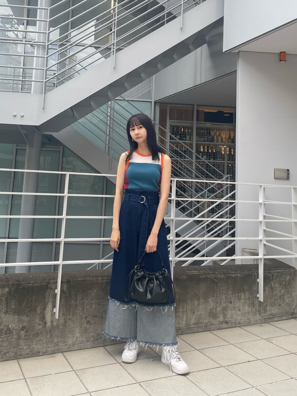 ブルー系のニット/セーター、ブラック系のハンドバッグ、ブルー系のデニムパンツを着用したレディースの春コーディネートの2枚目の写真