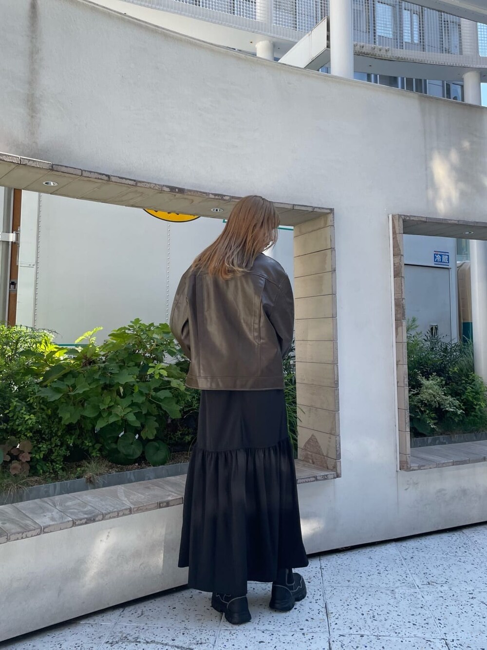 ブラック系のスカート、オレンジ系のニット/セーター、ブラック系のブーツを着用したレディースの秋コーディネートの4枚目の写真