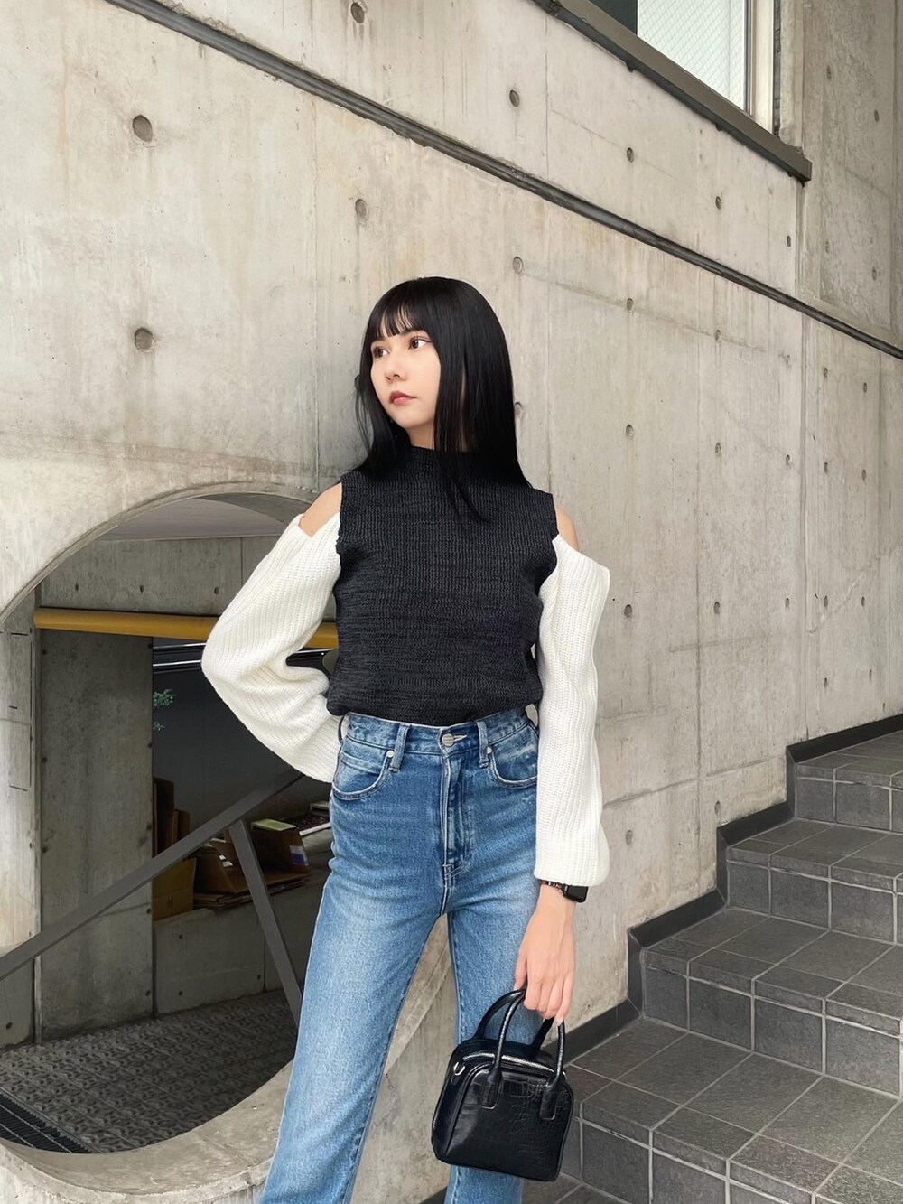 ブラック系のニット/セーター、ブラック系のブーツ、ブルー系のデニムパンツを着用したレディースの秋コーディネートの2枚目の写真