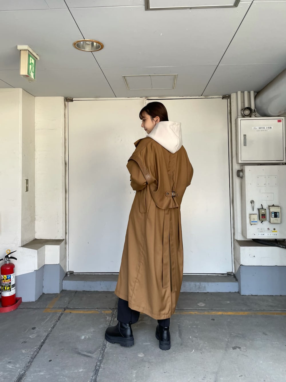 ブラウン系のトレンチコート、ブラック系のスラックス、ブラック系のブーツを着用したレディースの秋コーディネートの2枚目の写真