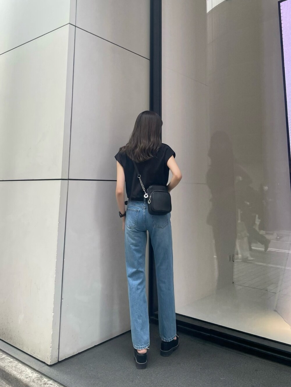 ブラック系のTシャツ/カットソー、ブルー系のデニムパンツ、ブラック系のサンダルを着用したレディースの春コーディネートの4枚目の写真