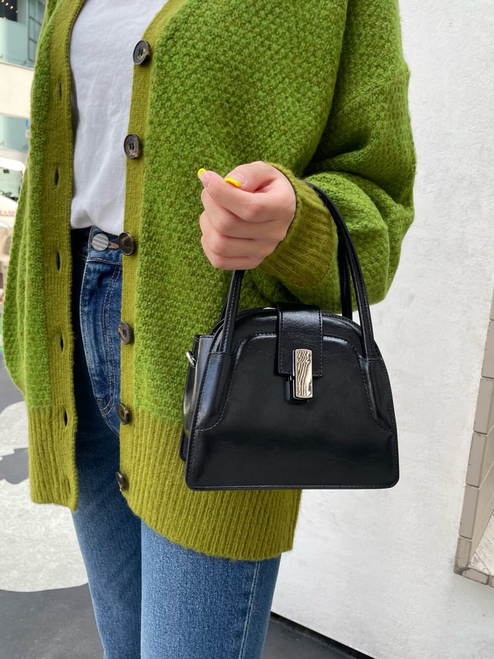 ブラック系のブーツ、ブルー系のデニムパンツ、ブラック系のハンドバッグを着用したレディースの春コーディネートの5枚目の写真
