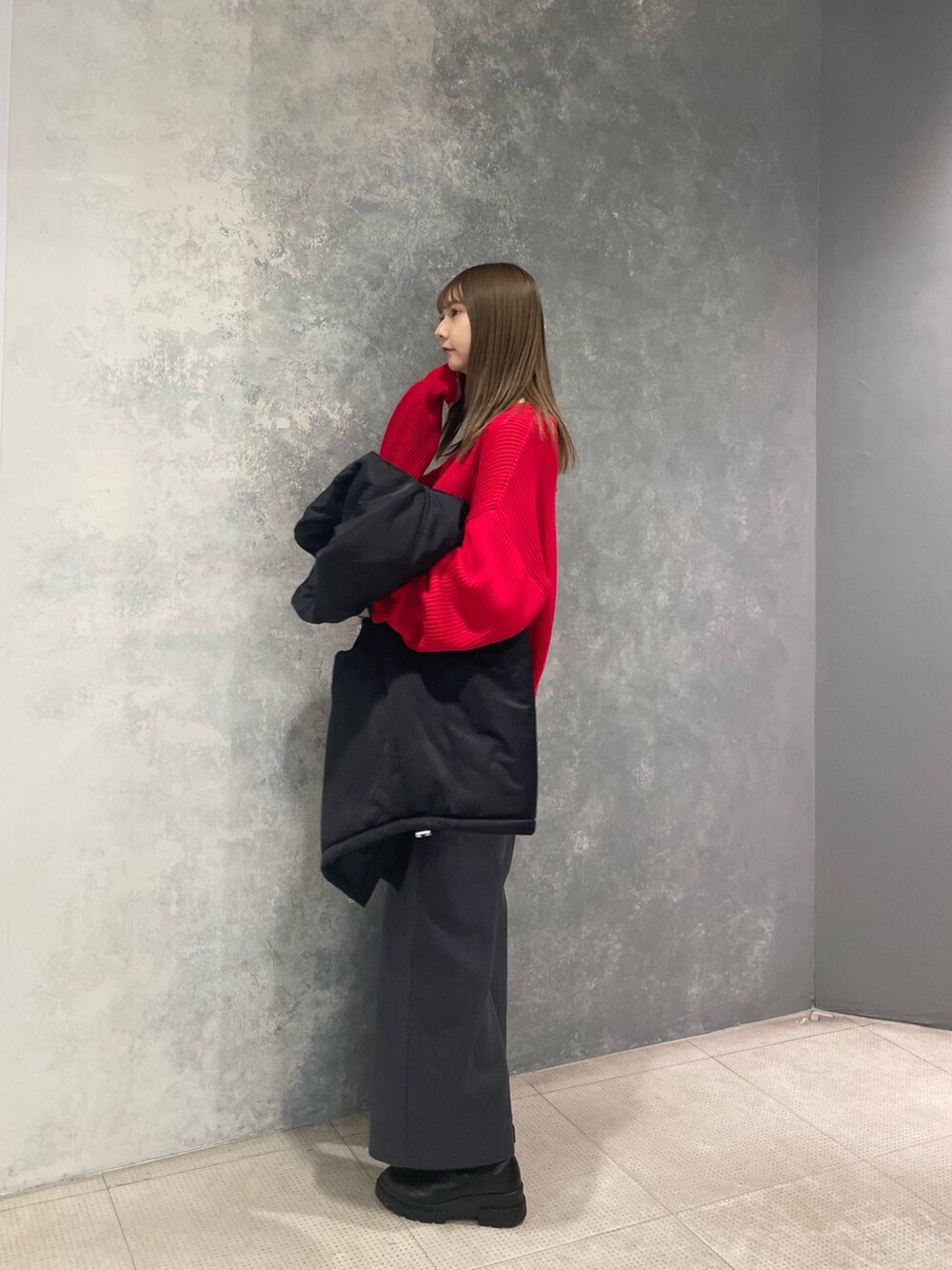 レッド系のニット/セーター、ブラック系のブルゾン、グレー系のスラックスを着用したレディースの冬コーディネートの3枚目の写真