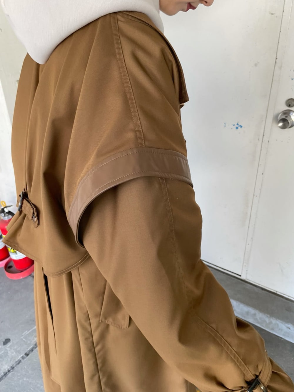 ブラウン系のトレンチコート、ブラック系のスラックス、ブラック系のブーツを着用したレディースの秋コーディネートの7枚目の写真