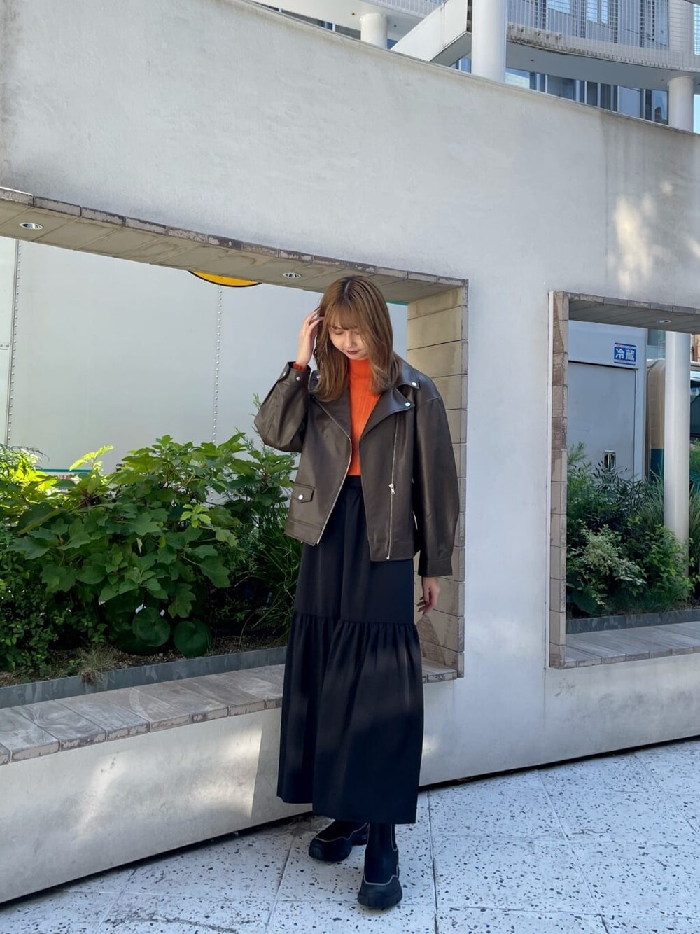 ブラック系のスカート、オレンジ系のニット/セーター、ブラック系のブーツを着用したレディースの秋コーディネートの2枚目の写真