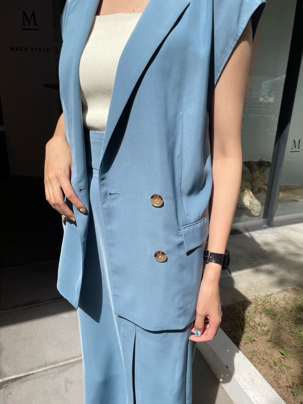 ブルー系のスカート、ブルー系のベスト、ブラック系のサンダルを着用したレディースの夏コーディネートの3枚目の写真