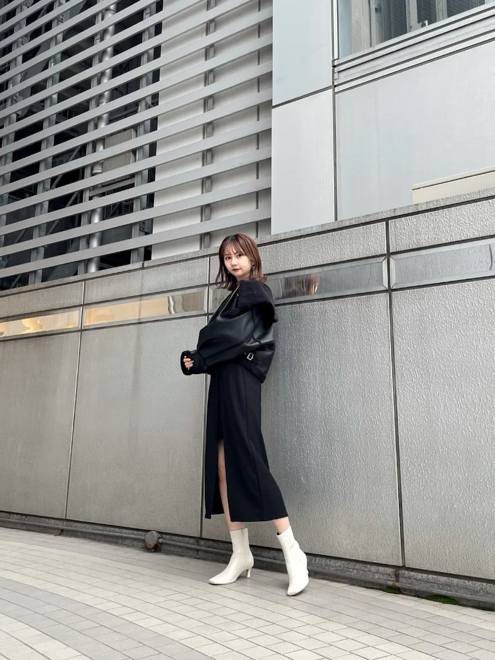 ブラック系のスカート、ブラック系のブルゾン、ホワイト系のブーツを着用したレディースの秋コーディネートの3枚目の写真