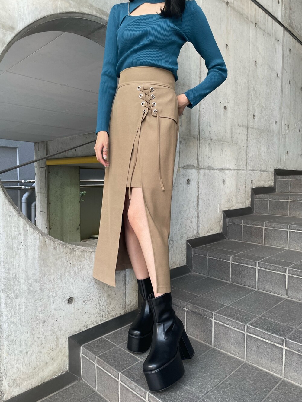 ブルー系のニット/セーター、ベージュ系のスカート、ブラック系のブーツを着用したレディースの夏コーディネートの6枚目の写真