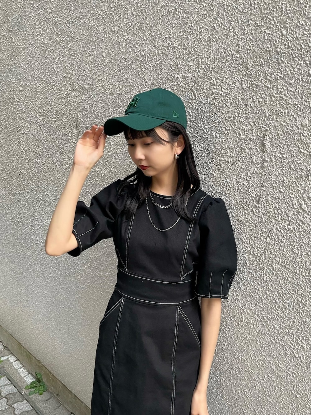 ブラック系のワンピース、ブラック系のブーツ、グリーン系のキャップを着用したレディースの春コーディネートの3枚目の写真