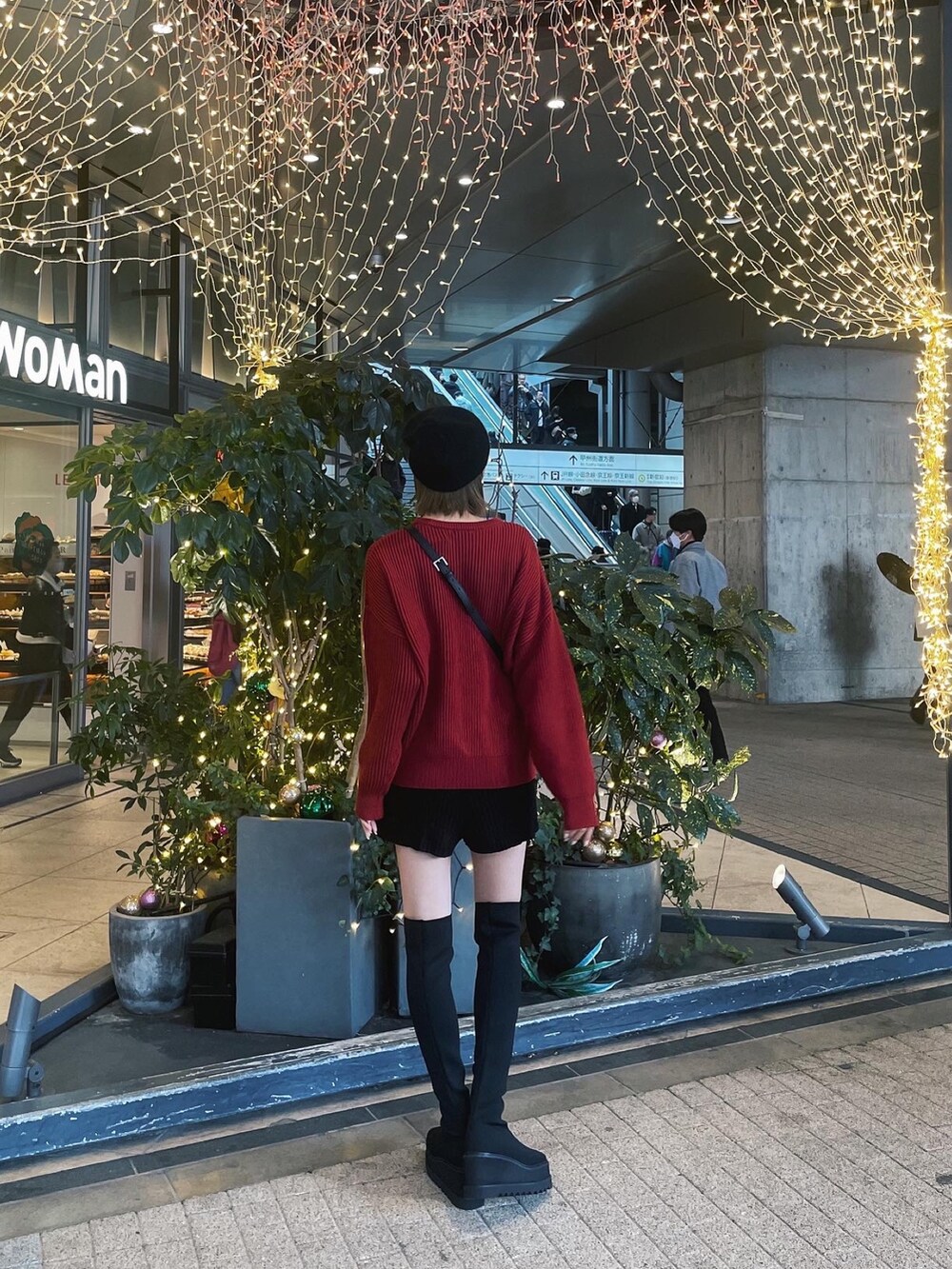 レッド系のニット/セーター、ブラック系のブーツ、ブラック系のニットキャップ/ビーニーを着用したレディースの冬コーディネートの2枚目の写真