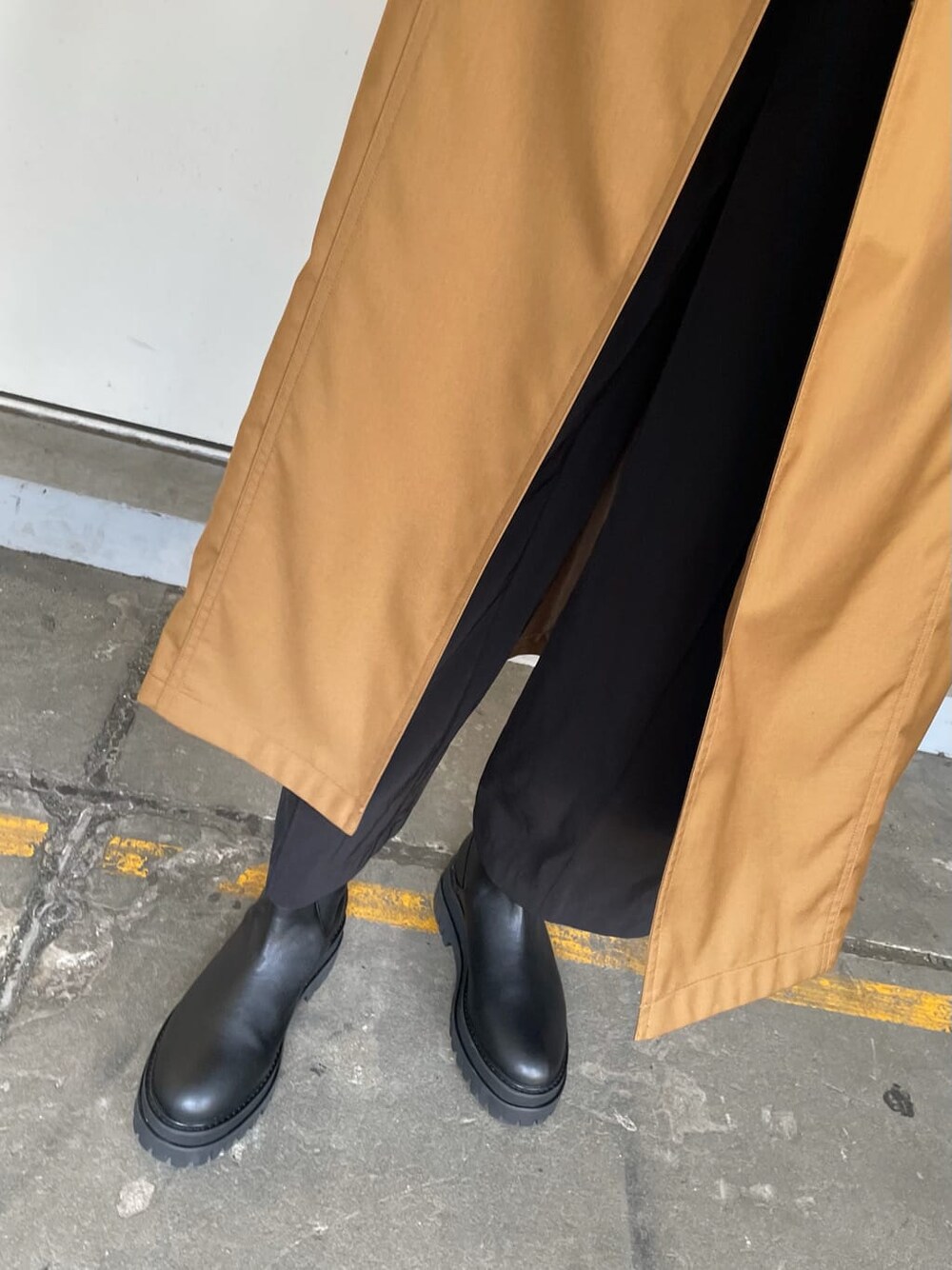 ブラウン系のトレンチコート、ブラック系のスラックス、ブラック系のブーツを着用したレディースの秋コーディネートの8枚目の写真