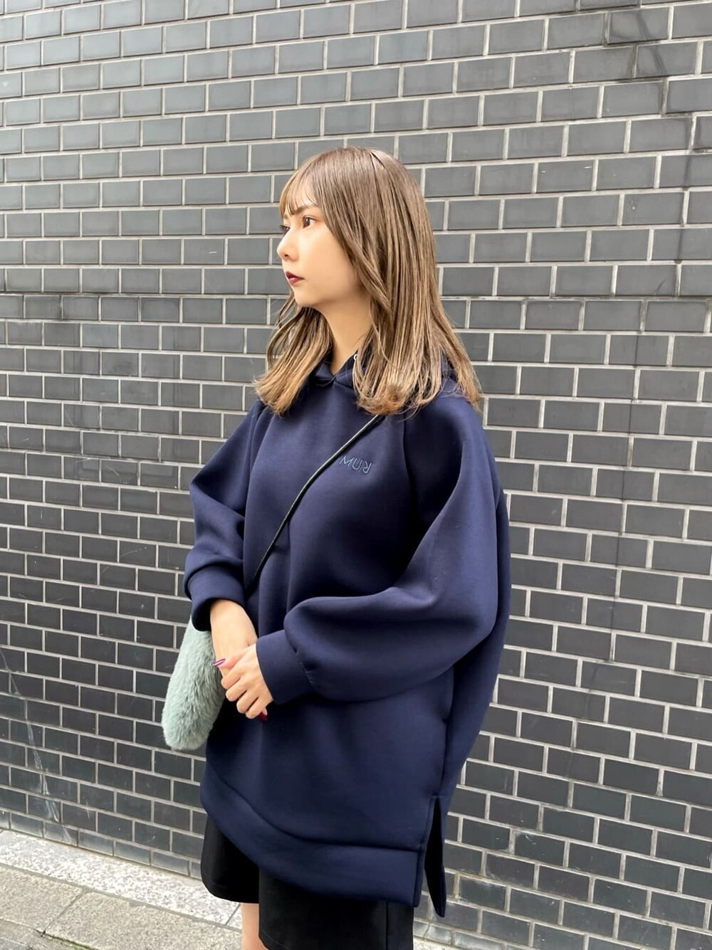 ホワイト系のブーツ、ベージュ系のショルダーバッグ、ブルー系のパーカーを着用したレディースの秋コーディネートの4枚目の写真