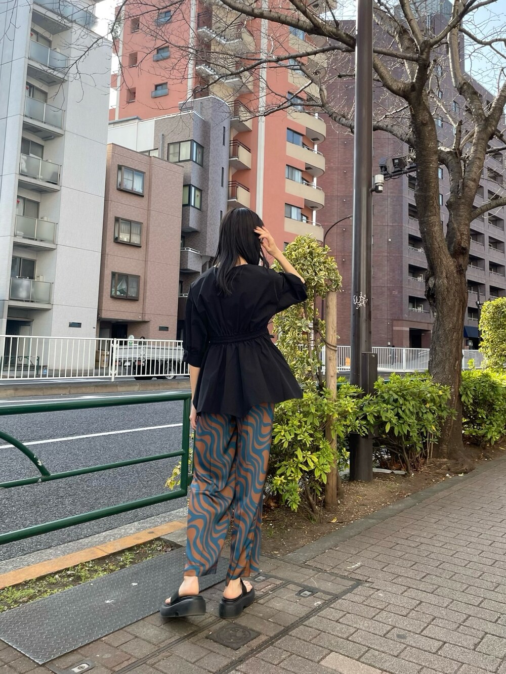 ブラック系のシャツ/ブラウス、ブルー系のスラックス、ブラック系のサンダルを着用したレディースの春コーディネートの3枚目の写真