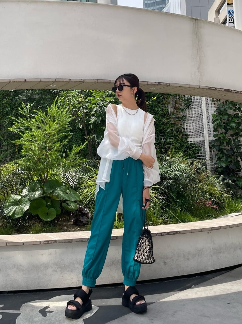 ブラック系のハンドバッグ、ホワイト系のシャツ/ブラウス、ブラック系のサンダルを着用したレディースの夏コーディネートの2枚目の写真