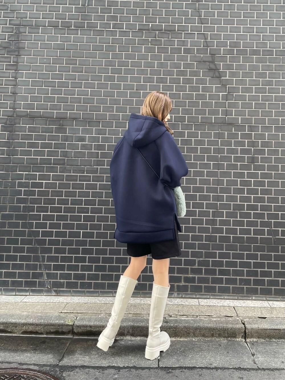 ホワイト系のブーツ、ベージュ系のショルダーバッグ、ブルー系のパーカーを着用したレディースの秋コーディネートの3枚目の写真